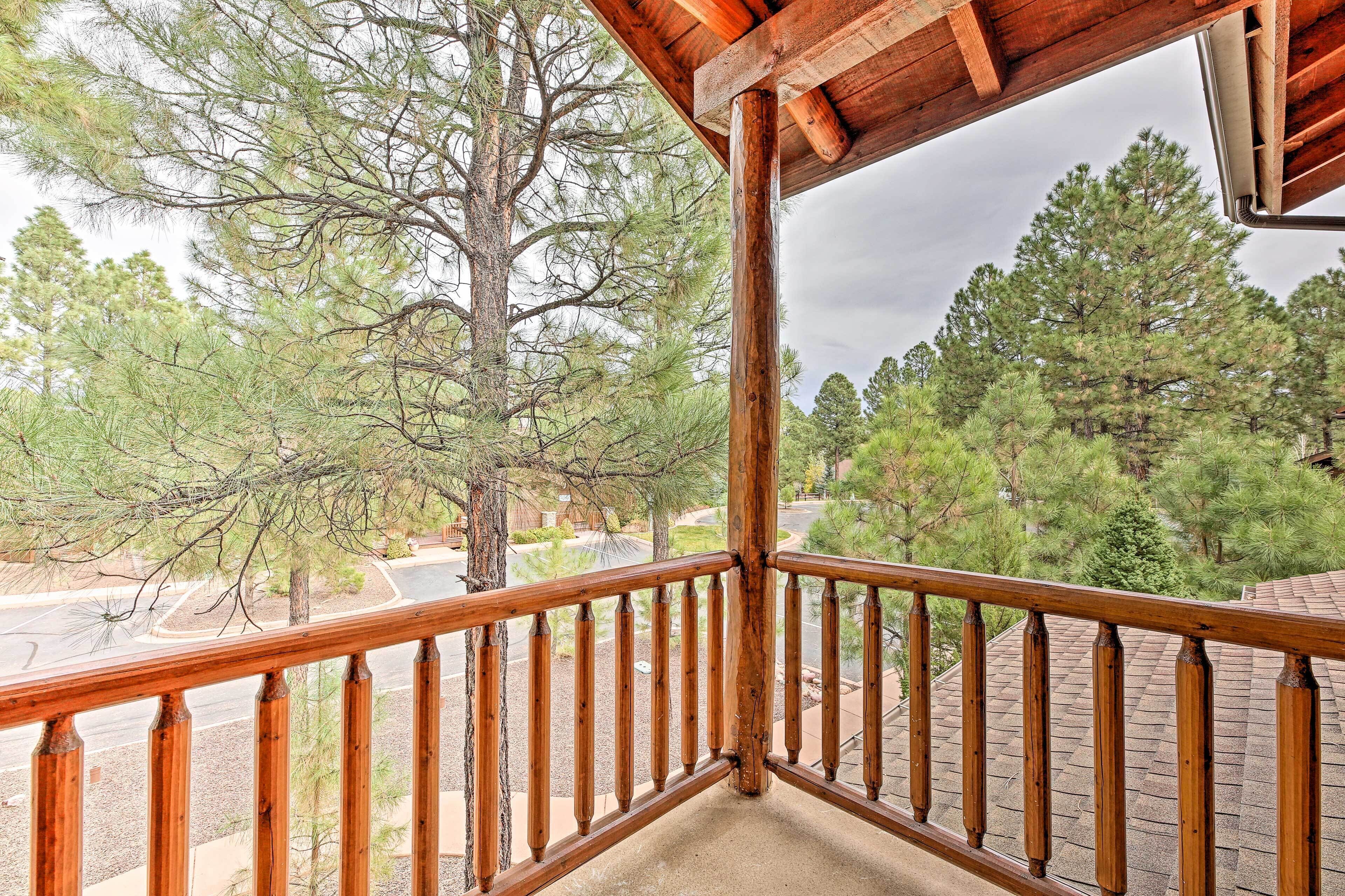 A wooden balcony railing overlooking a road and trees.