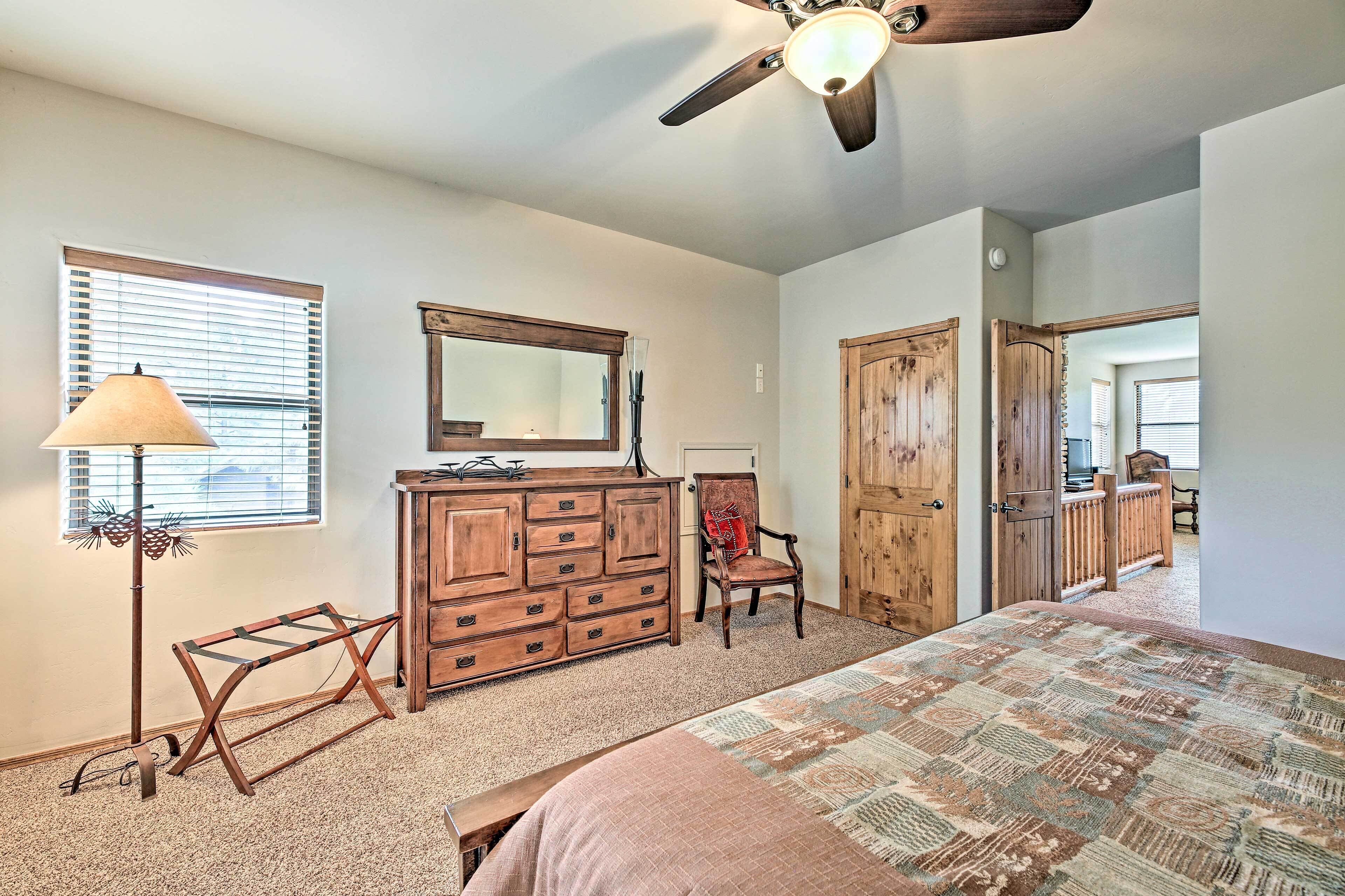 A bedroom with a bed, dresser, chair, and a ceiling fan.
