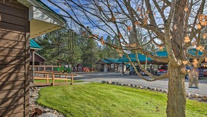 A building with a green roof, a grassy lawn, and a tree with autumn leaves. - Pet-friendly Libby Cottage w/ Mountain Views! (Libby)