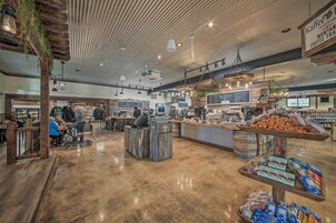 Una cafetería amplia con un interior rústico de madera, diversas opciones de asientos y una exhibición de granos de café y pasteles.