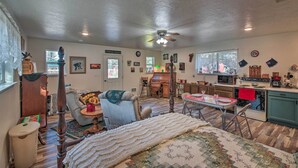 A cozy room with a bed, a chair, a dining table, and a kitchen area. - Pet-friendly Libby Cottage w/ Mountain Views! (Libby)