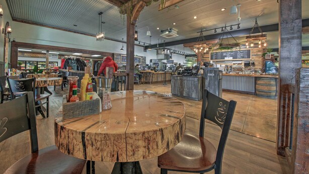 A restaurant with a rustic interior, featuring exposed wooden beams, a central round wooden table, and a variety of seating options. - Pet-friendly Libby Cottage w/ Mountain Views! (Libby)
