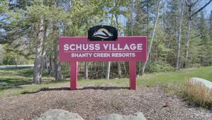Schild für Schuss Village Shanty Creek Resort mit Logo oberhalb des Textes.