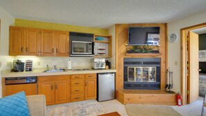 Eine kleine Küche mit Holzschränken, einer Mikrowelle, einem Toaster und einem Kühlschrank.