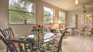 A dining area with a glass-top table surrounded by chairs, large windows with views of trees, and a ceiling fan. - Pet-friendly Flagler Beach Home w/ Yard Near Beach (Flagler Beach)