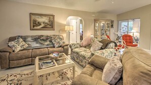 A living room with a brown sofa, a floral armchair, and a glass coffee table. - Pet-friendly Flagler Beach Home w/ Yard Near Beach (Flagler Beach)