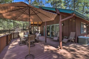 A covered deck with outdoor furniture, a grill, and a hot tub. - Deck w/ Wooded Views: Rustic-chic Prescott Cabin! (Prescott)