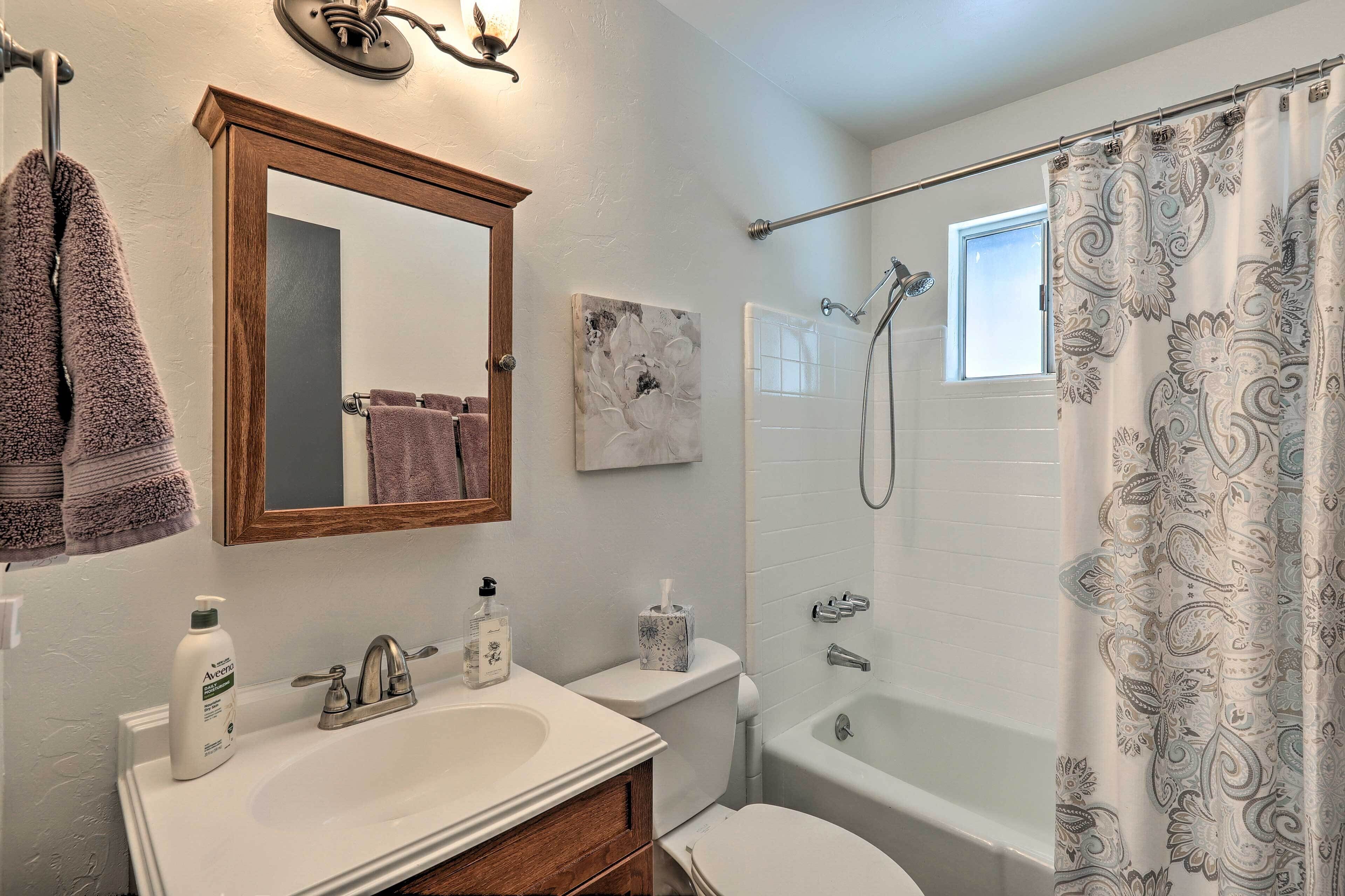 A bathroom with a sink, mirror, and shower.