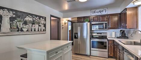 A modern kitchen with white cabinetry, stainless steel appliances, and a wooden floor.