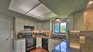 Una cocina moderna con una isla central, electrodomésticos integrados y un ventanal que proporciona luz natural.