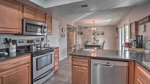 A modern kitchen with wooden cabinets, stainless steel appliances, and a central island. - Phoenix Family Home w/ Pool + Playground! (Phoenix)