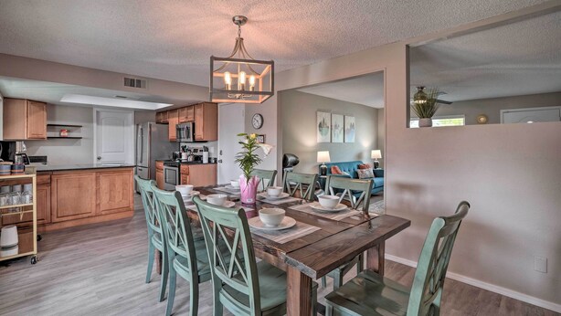 A modern kitchen with wooden cabinets, a dining table set with chairs, and a chandelier. - Phoenix Family Home w/ Pool + Playground! (Phoenix)