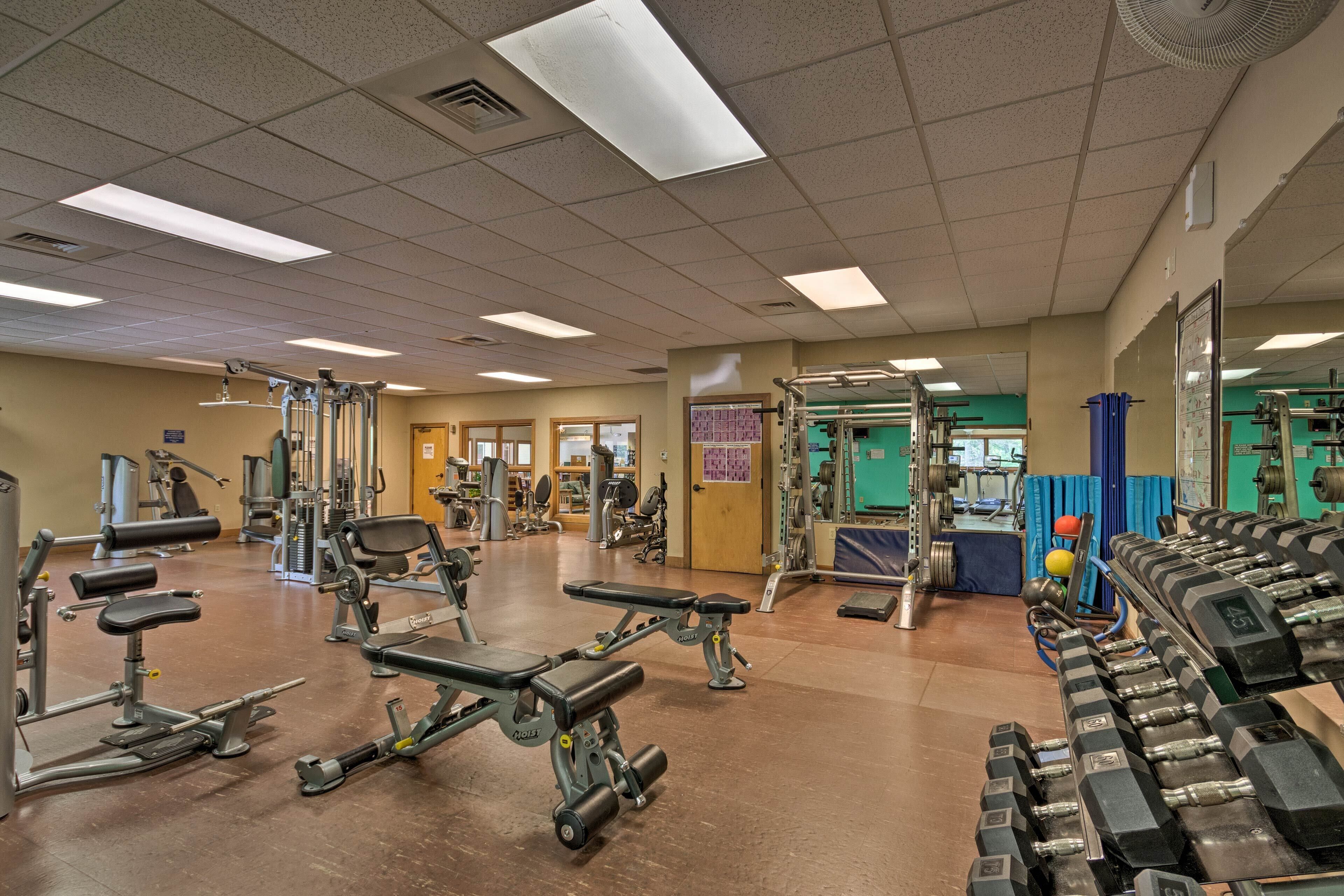 A gym with various exercise equipment, including treadmills, weight machines, and dumbbells.