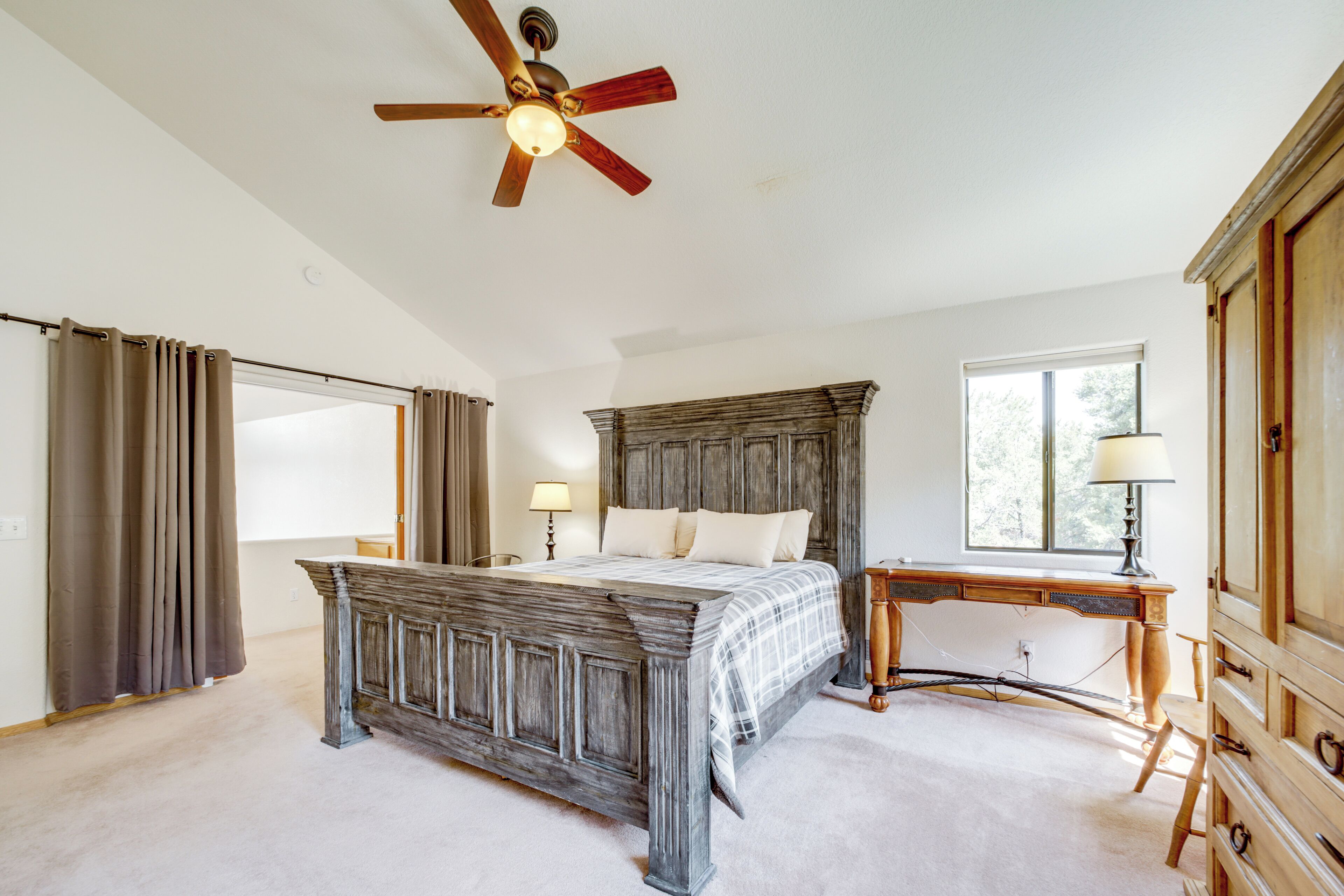 A bedroom with a wooden bed, a desk, and a ceiling fan.