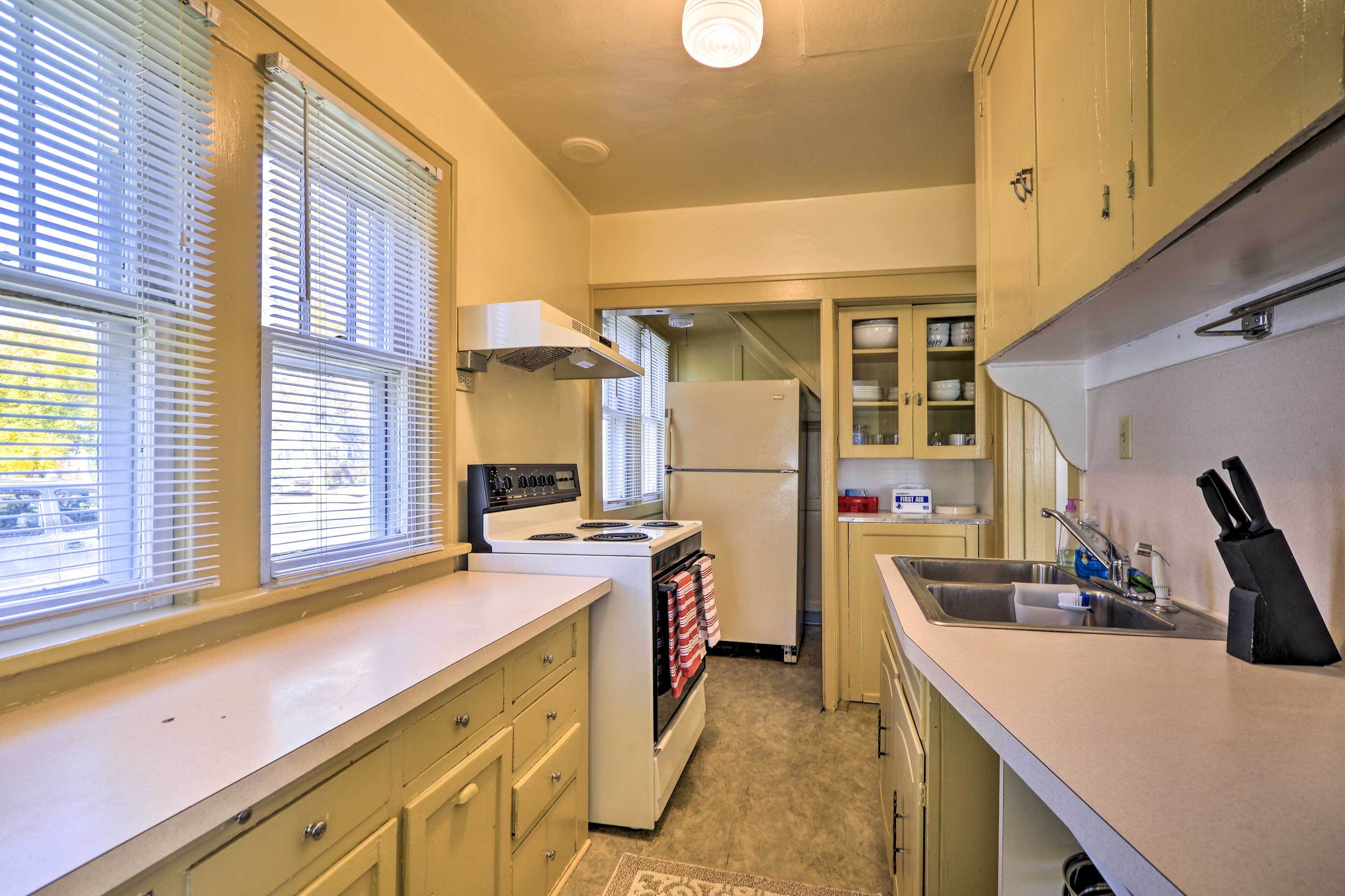 A compact kitchen with a stove, oven, refrigerator, and a sink.