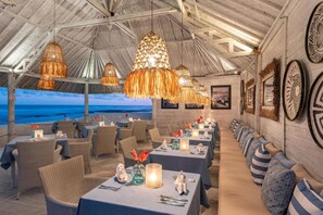 Enjoy a refined dining experience with ocean views, surrounded by artwork and elegant table settings.