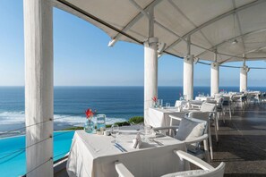 Dine with a view of the ocean at this seaside restaurant, featuring elegant tables and comfortable seating.