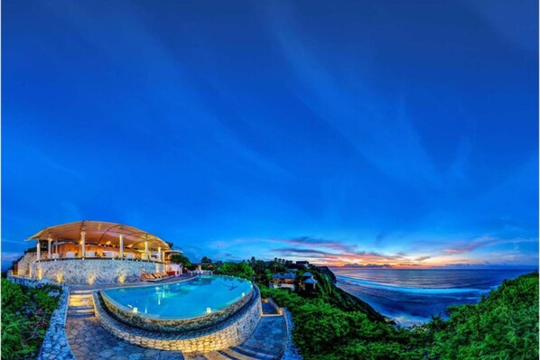 Relax by the infinity pool overlooking the ocean's horizon, surrounded by a comfortable outdoor lounge area.