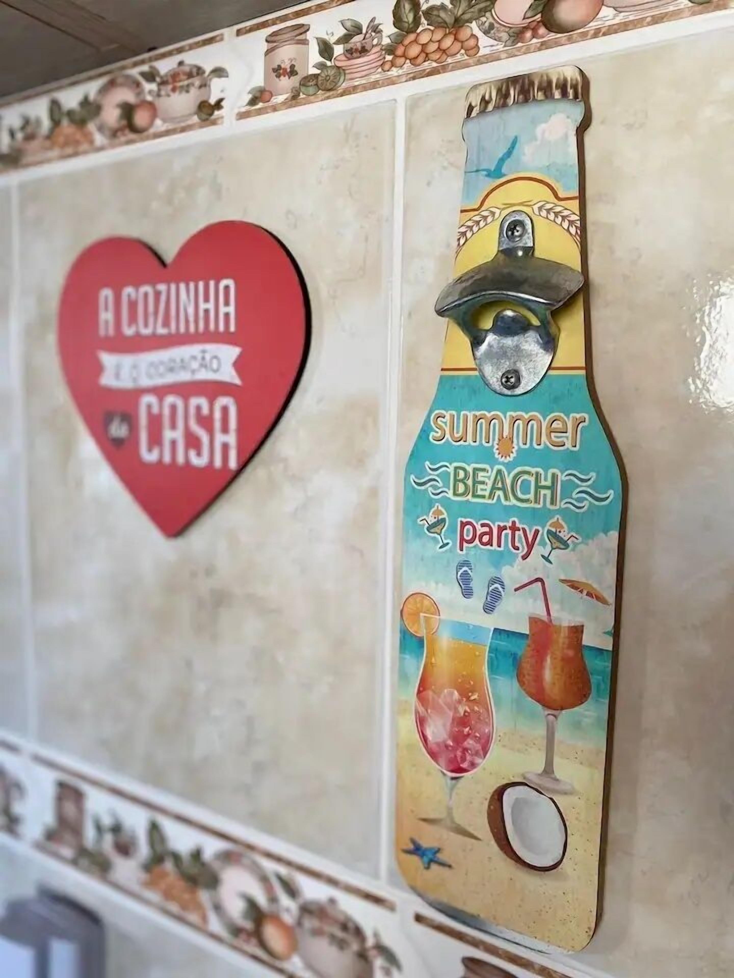A wall with a heart-shaped sign reading "A COZINHA é a CORAÇÃO da CASA" and a vertical sign with a beach theme, including a drink and a straw.