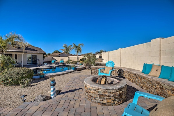 A backyard with a swimming pool, a fire pit, and outdoor seating.