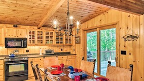 L’intérieur d’un chalet en bois comprend une salle à manger avec une table dressée pour quatre personnes, une cuisine avec des meubles en bois, un four à micro-ondes et une cuisinière.