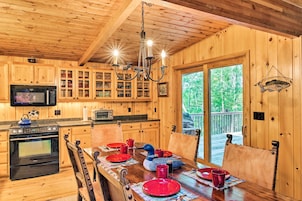 Interior de una cabaña de madera con una mesa de comedor para cuatro, una cocina con armarios de madera, un microondas y una estufa.