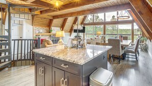 A spacious kitchen with a large island, wooden beams, and a view of the outdoors. - Flagstaff A-frame Cabin w/ Deck & Lovely Views! (Flagstaff)