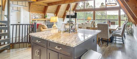 A spacious kitchen with a large island, wooden beams, and a view of the outdoors.