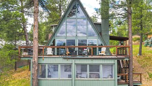 A cabin with a large glass front, wooden deck, and a staircase leading to the upper level. - Flagstaff A-frame Cabin w/ Deck & Lovely Views! (Flagstaff)