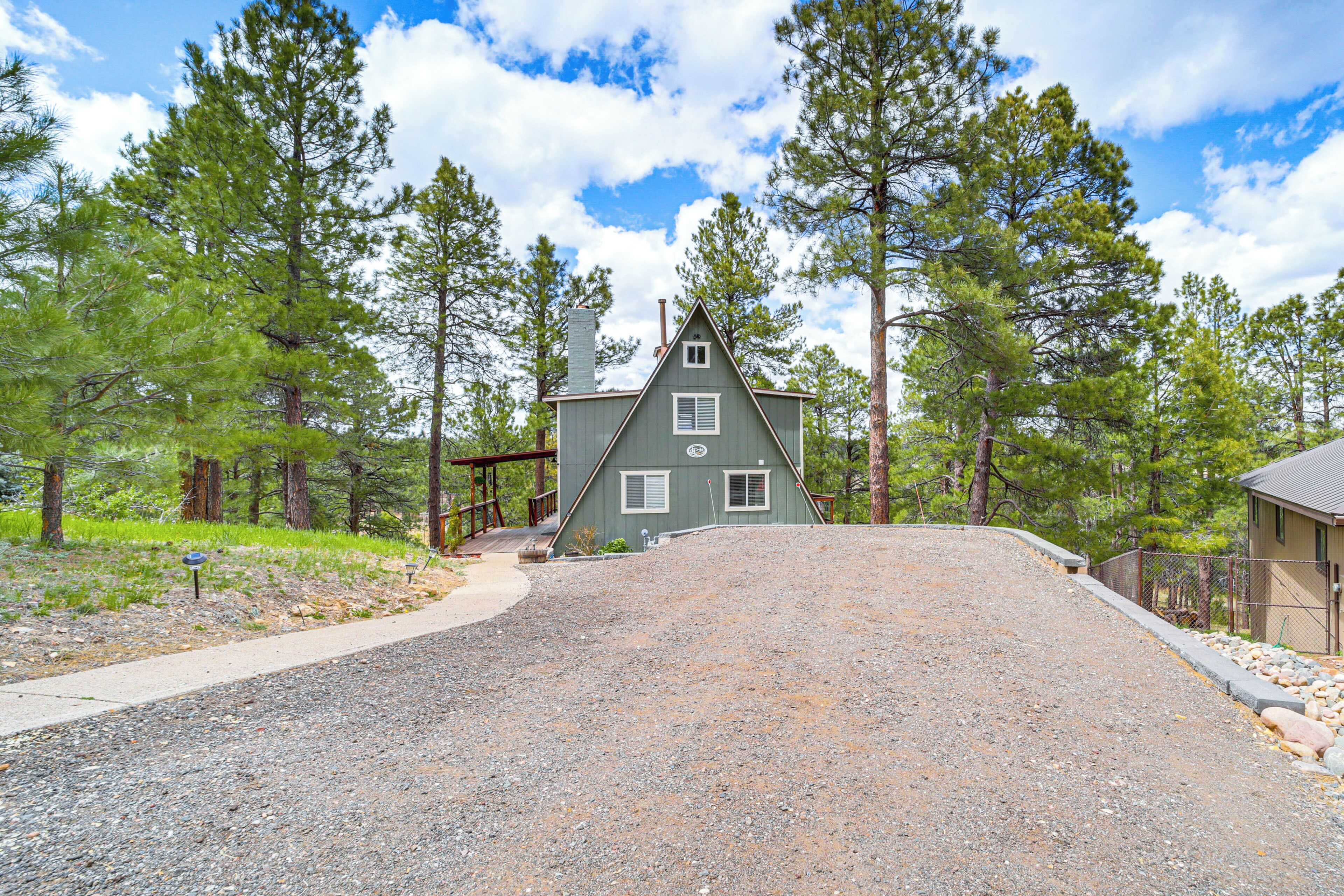A house with a sloped roof, surrounded by a gravel driveway, and a wooden deck.