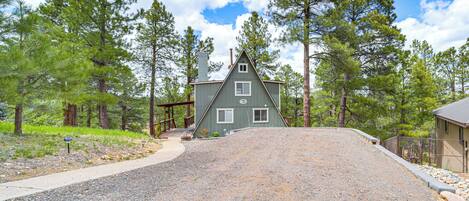 A house with a sloped roof, surrounded by a gravel driveway, and a wooden deck.