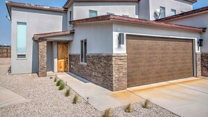 A modern two-story house with a stone facade, a wooden garage door, and a clear sky. - Upscale Moab Home w/ Red Rock Views & Hot Tub (Moab)