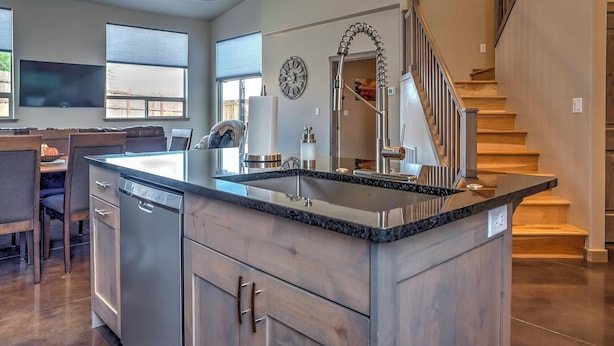 A modern kitchen with a large island, stainless steel appliances, and a staircase leading to an upper level. - Upscale Moab Home w/ Red Rock Views & Hot Tub (Moab)