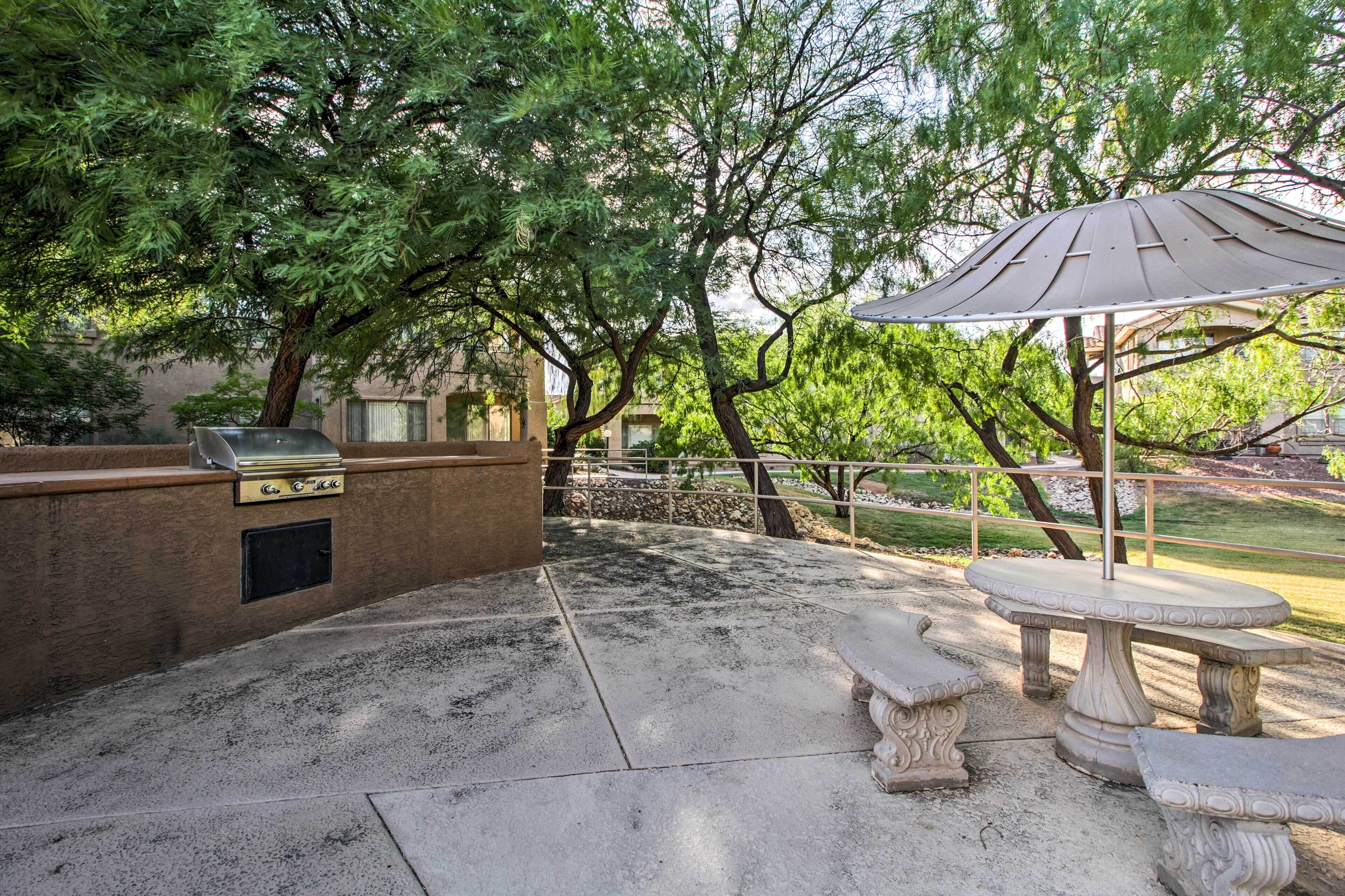 Un patio al aire libre con una parrilla, una mesa de piedra y bancos.