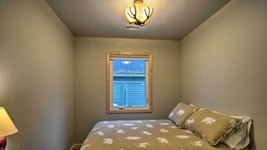 Une chambre à coucher avec un lit, une fenêtre et un luminaire au plafond.