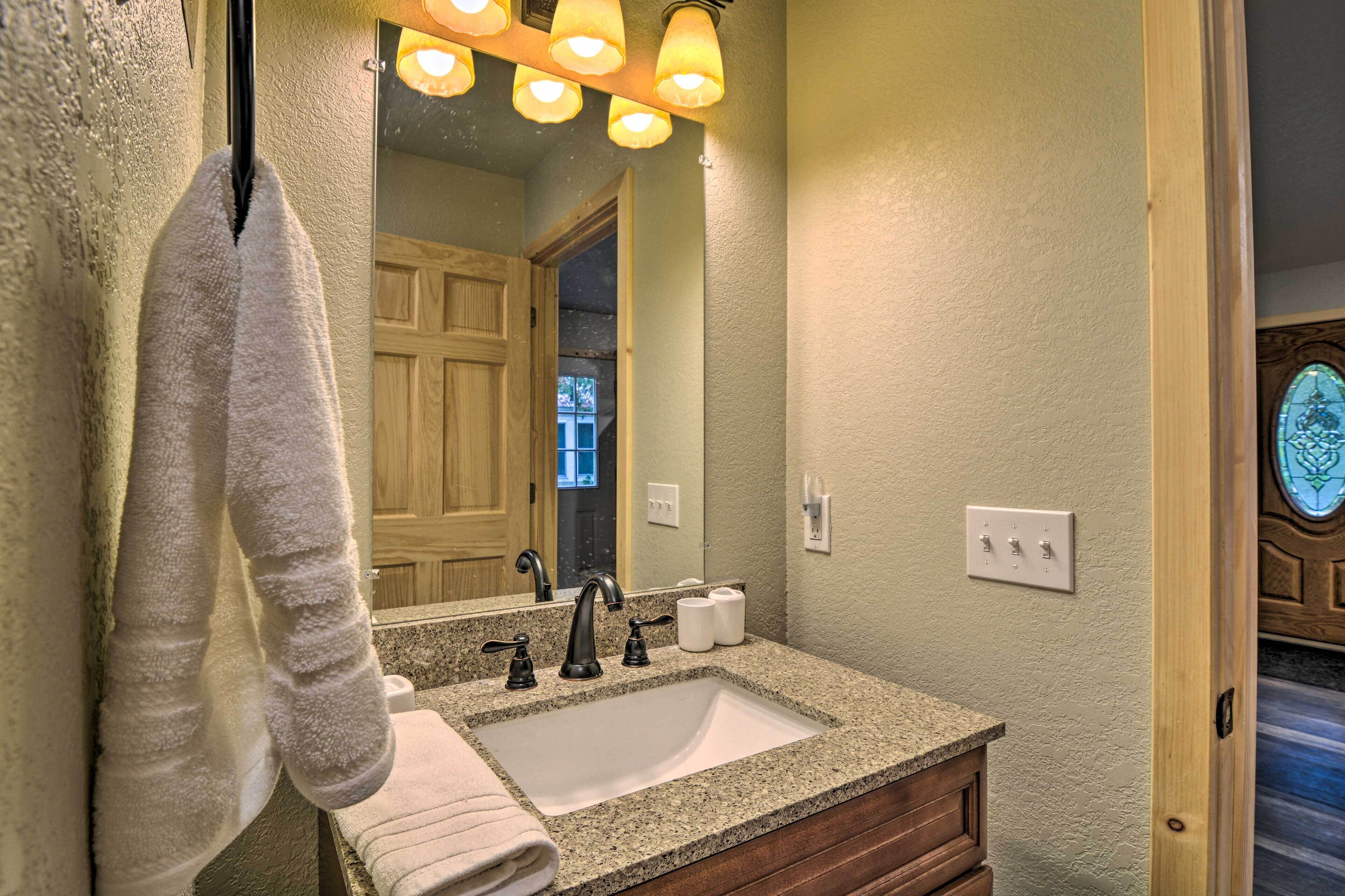 A bathroom with a granite countertop sink, a mirror, and a towel hanging on the wall.