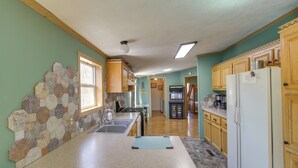 A kitchen with a stone backsplash, wooden cabinets, and a refrigerator.