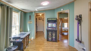 A hallway with a jukebox, a vacuum cleaner, and a bed in the background.
