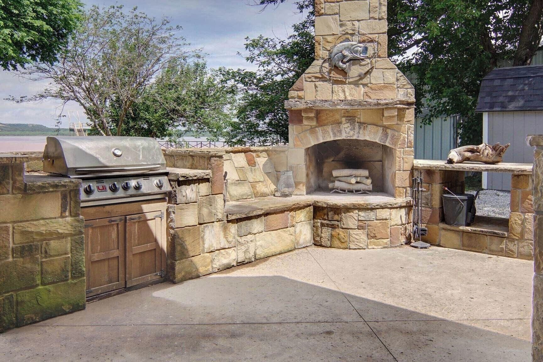 An outdoor kitchen with a stone oven, grill, and a wooden cabinet.