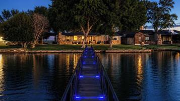A wooden pathway over water leading to a building with stone walls and a covered area.