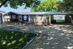 A building with a covered porch, a gravel driveway, and a fenced area with a dock. - Possum Kingdom Waterfront Retreat w/ Pier, Bar (Graford)