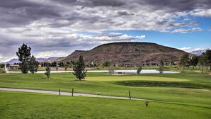 Un parcours de golf avec un étang, des arbres et une colline en arrière-plan.