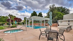 Un espace piscine doté d’un coin salon couvert, de chaises longues et d’une table.