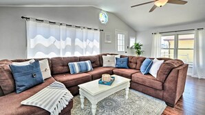 Ein Wohnzimmer mit einem braunen Ecksofa, einem weißen Couchtisch und einem Deckenventilator.