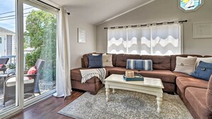 Ein Wohnzimmer mit einem braunen Ecksofa, einem weißen Couchtisch und einem gemusterten Teppich.