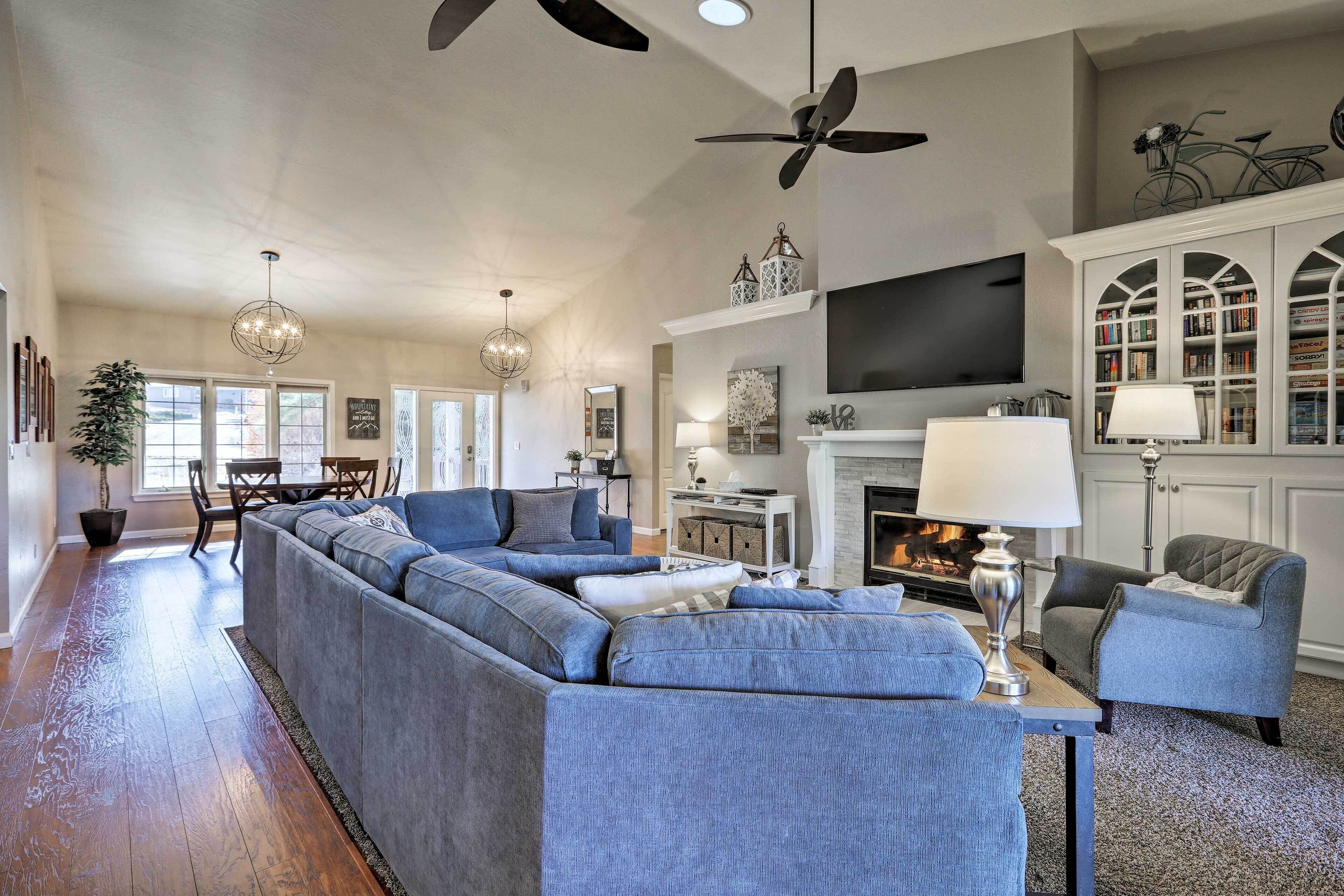 A spacious living room with a sectional sofa, a fireplace, a television, and a bookshelf.