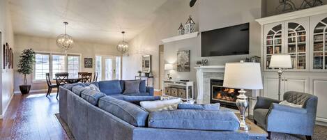 A spacious living room with a sectional sofa, a fireplace, a television, and a bookshelf.