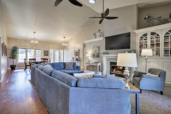 A spacious living room with a sectional sofa, a fireplace, a television, and a bookshelf.