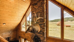 A room with a stone wall, a mounted elk head, and a clock. - Cozy Family Cabin: Game Room, Near National Parks! (Duck Creek Village)