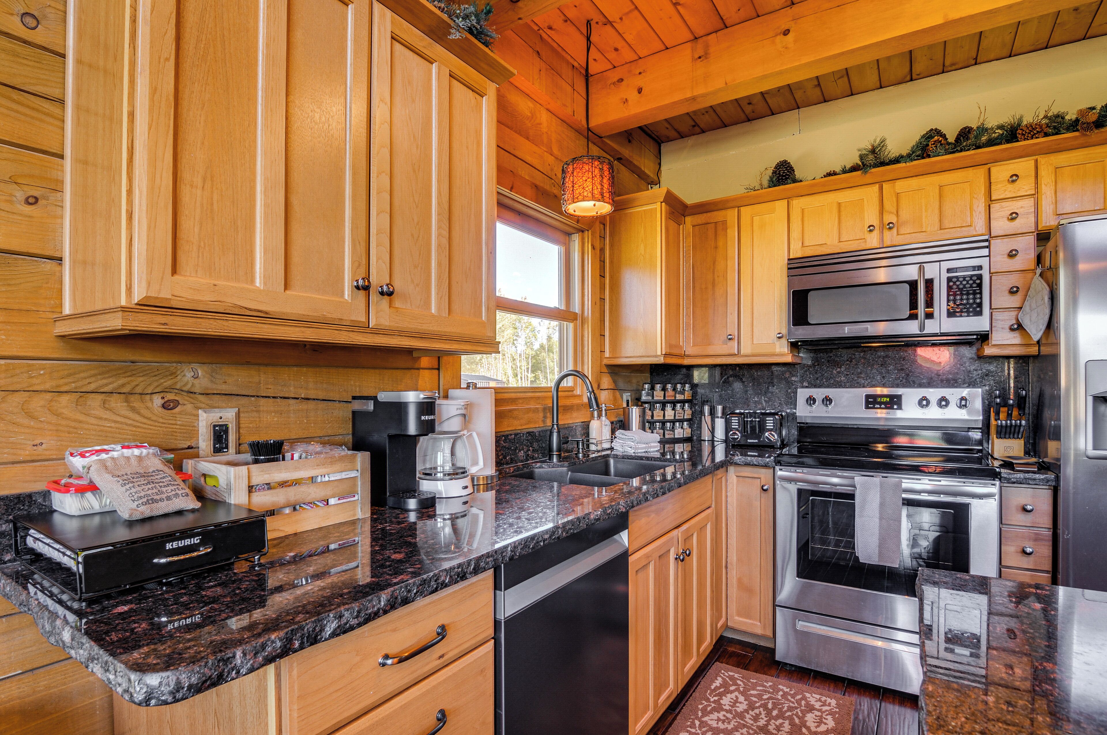 A kitchen with wooden cabinets, a granite countertop, stainless steel appliances, and a coffee maker.
